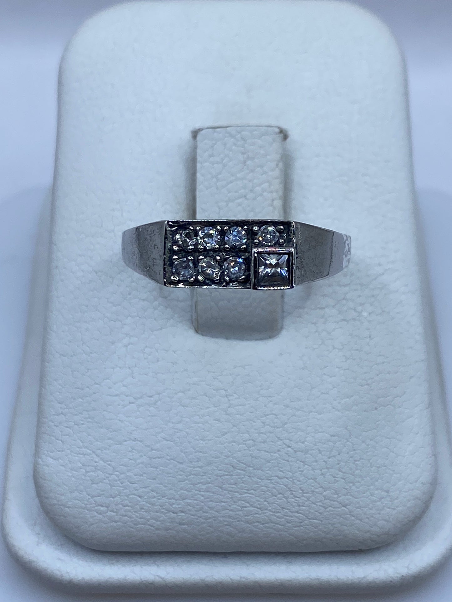 Anillo de plata minimalista con circonia blanca brillante, vista frontal en bandeja blanca