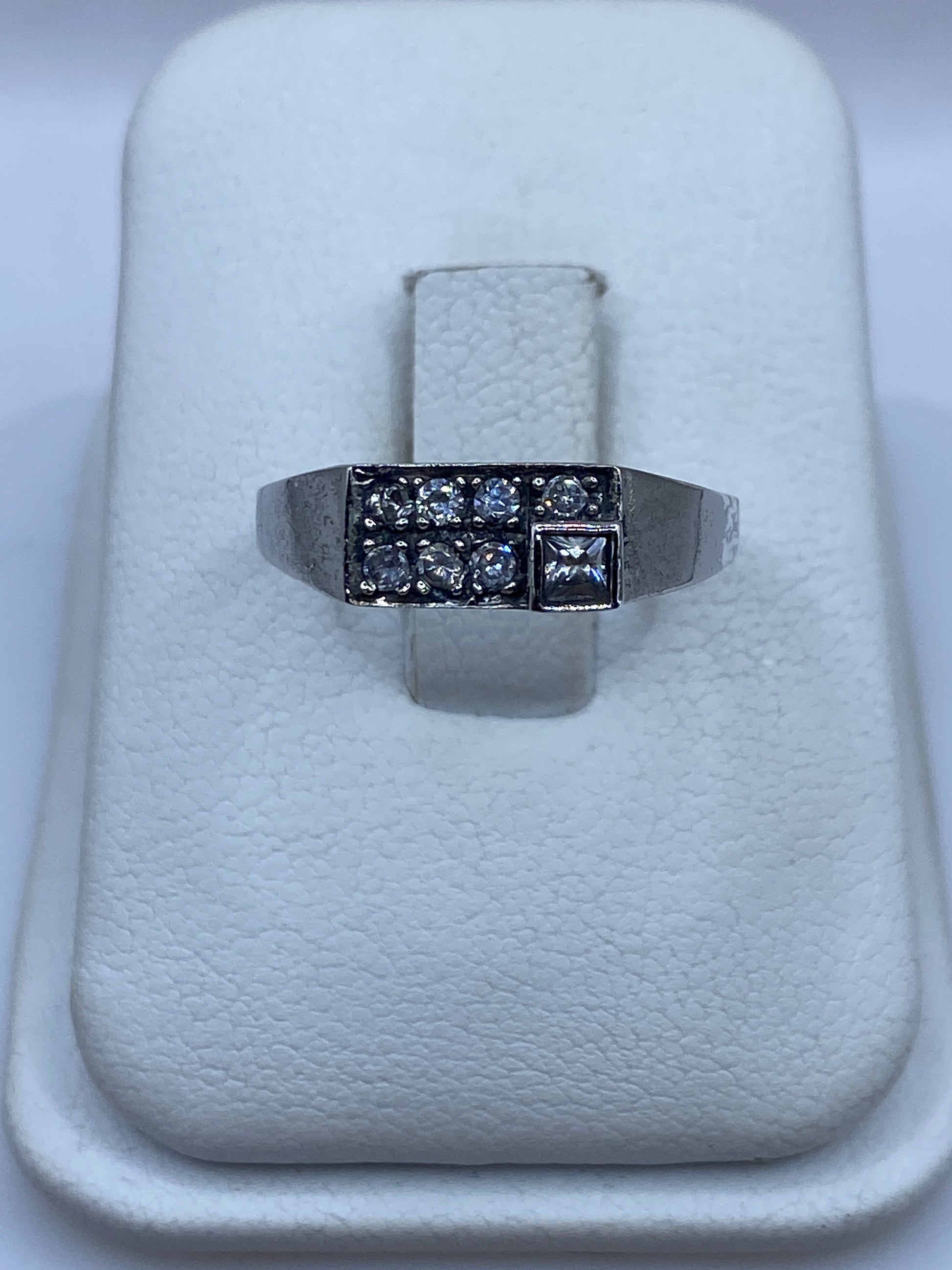Anillo de plata minimalista con circonia blanca brillante, vista frontal en bandeja blanca