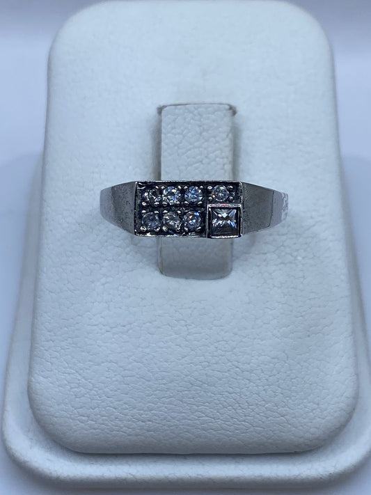 Anillo de plata minimalista con circonia blanca brillante, vista frontal en bandeja blanca