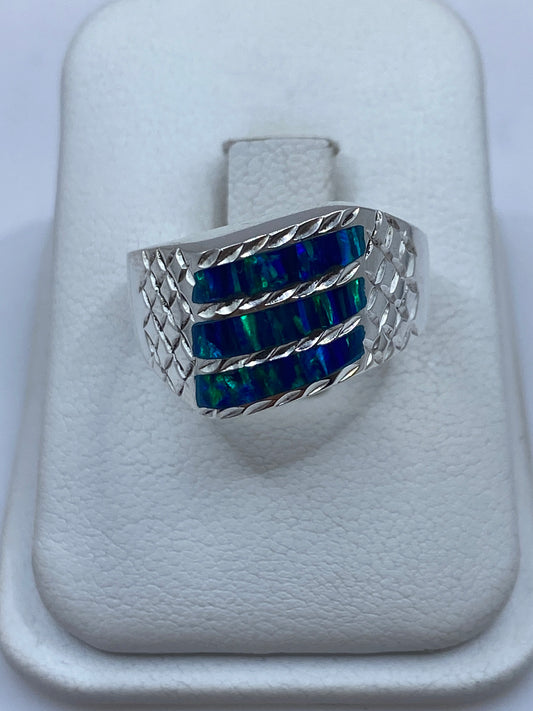 Anillo de plata .950 con ópalo de fuego azul y banda texturizada en estuche blanco