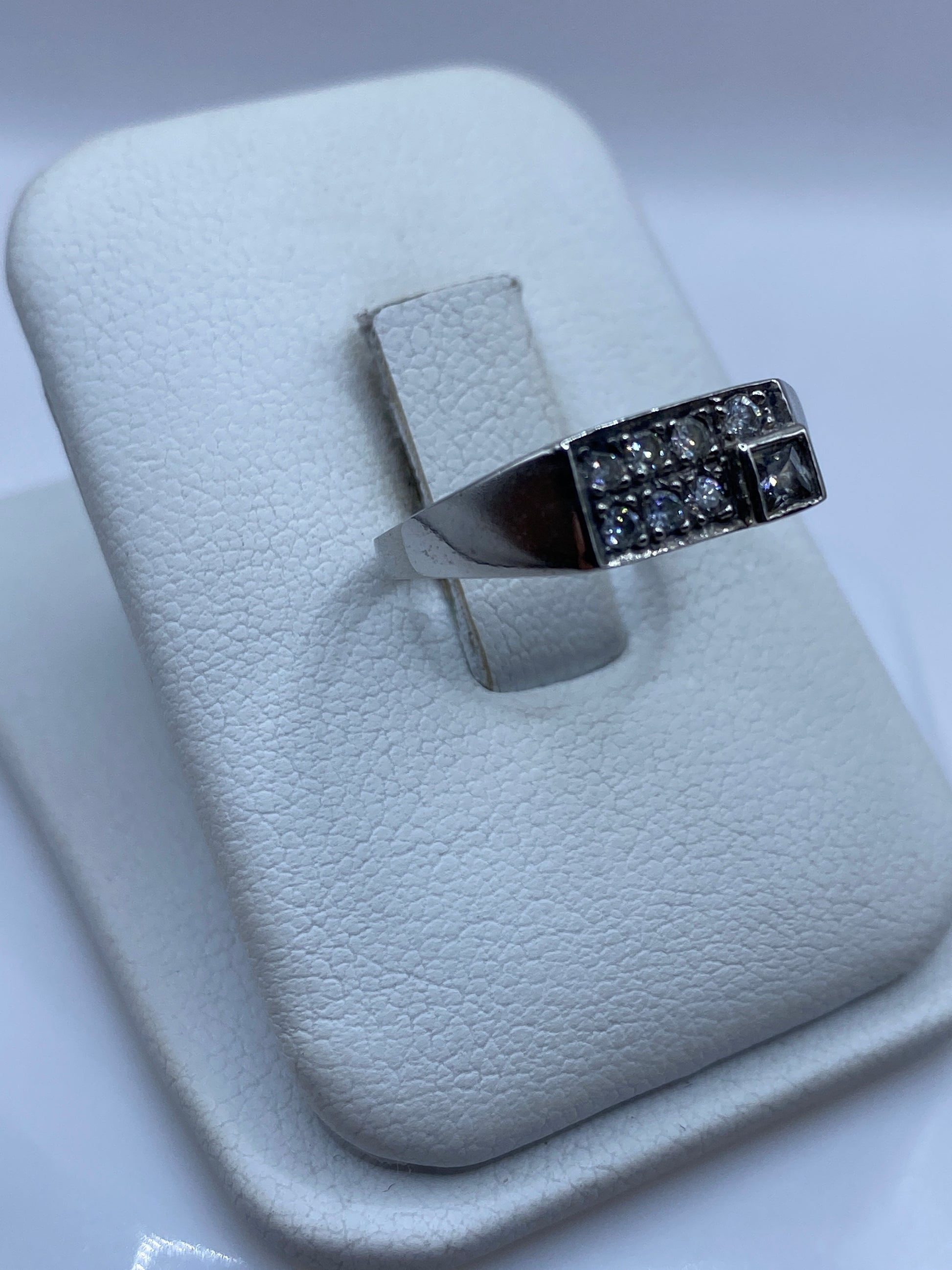 Vista frontal del anillo de plata .925 con piedra blanca en mano de mujer