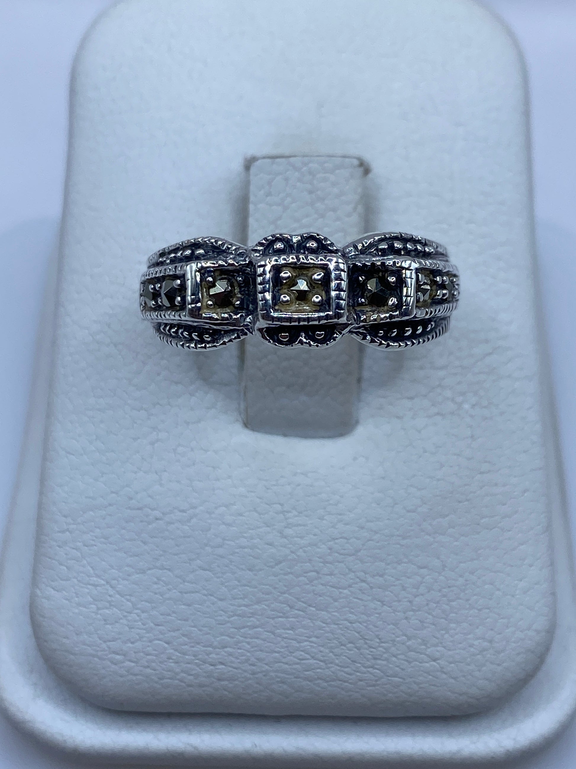 Anillo de plata .925 con tres compartimentos texturizados en la mano de una mujer
