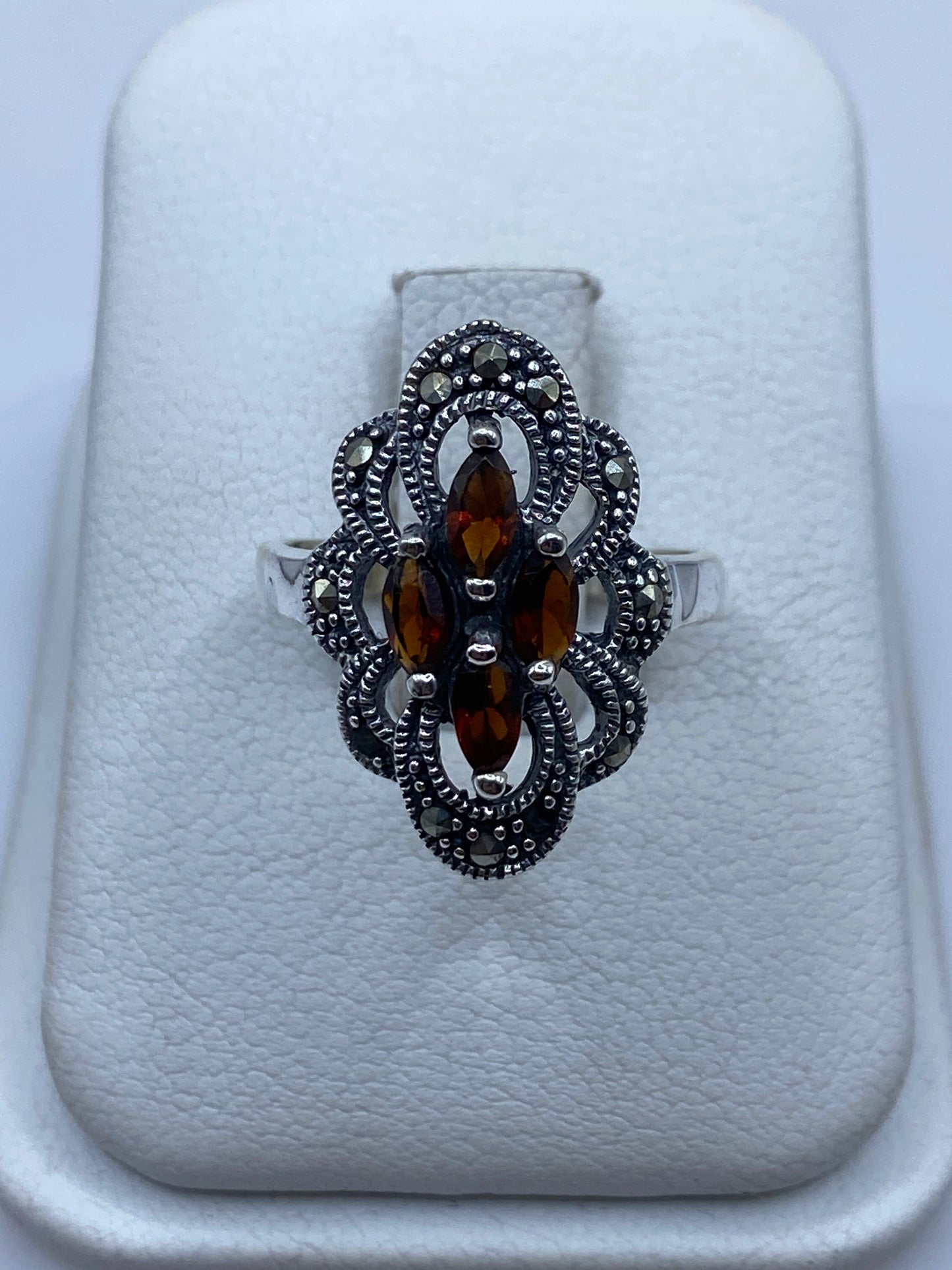 Anillo vintage de plata con ámbar natural y filigrana, reposo sobre almohadilla blanca