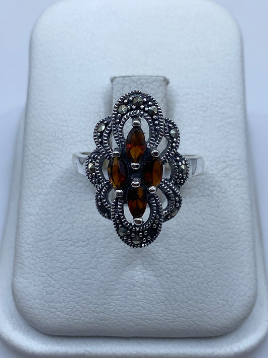 Anillo vintage de plata con ámbar natural y filigrana, reposo sobre almohadilla blanca