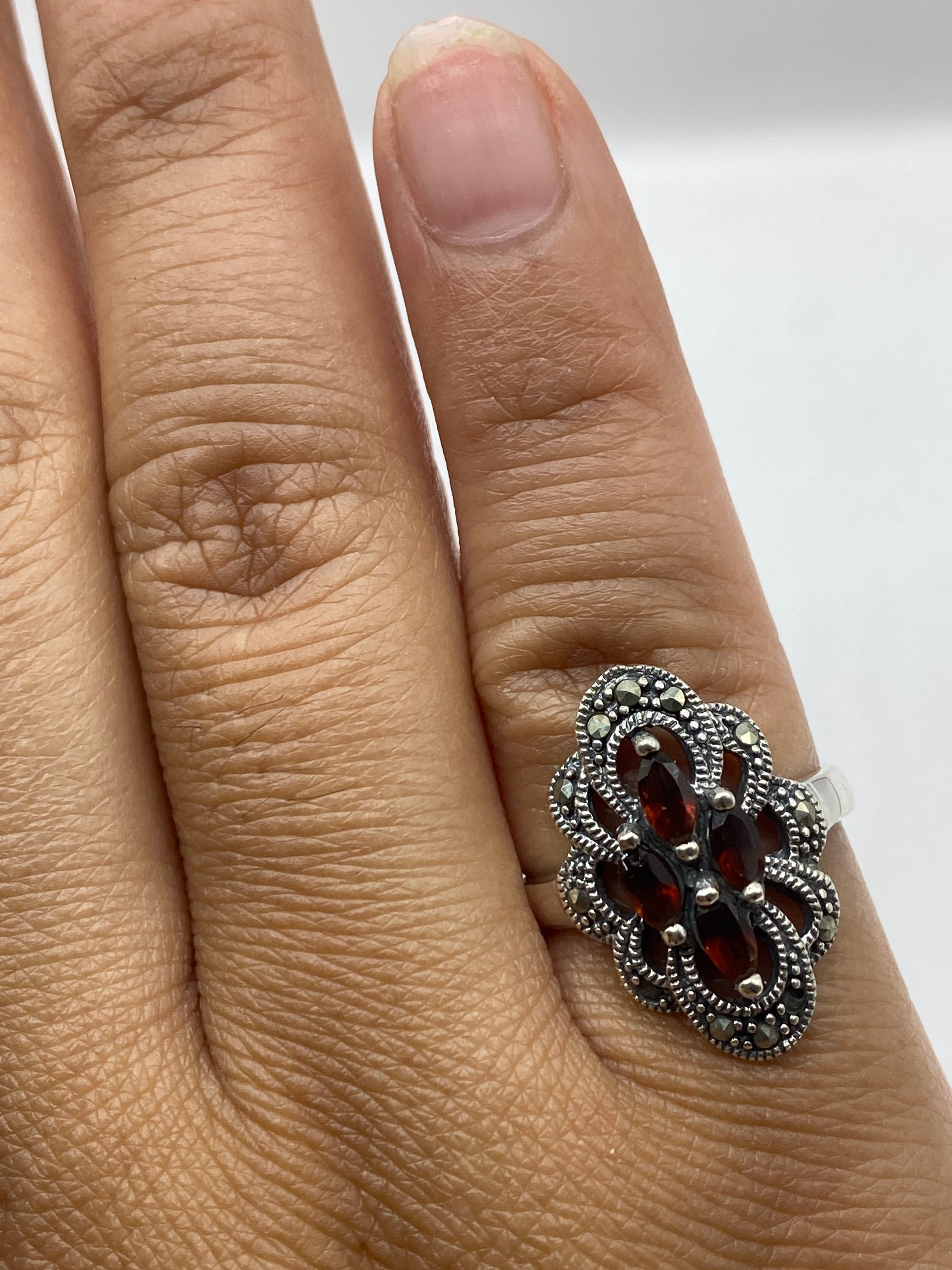 Anillo en mano mostrando el brillo cálido del ámbar natural en tonalidades miel y rojo profundo