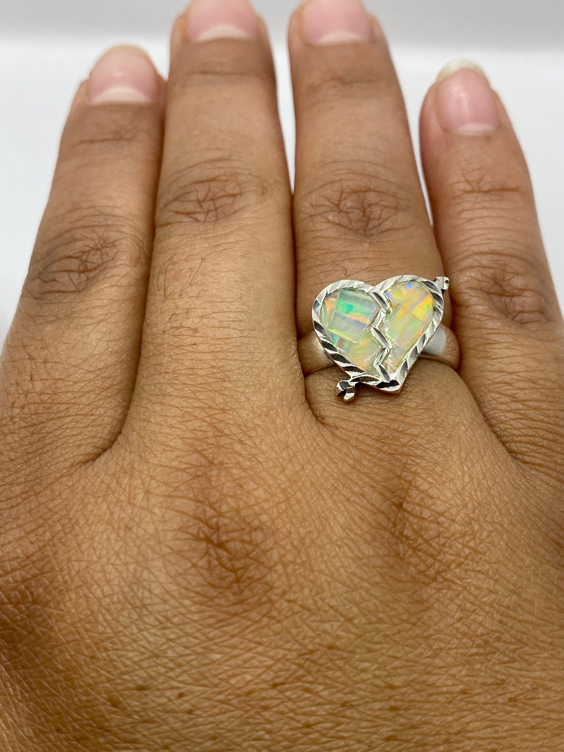 Anillo en dedo femenino mostrando el juego de colores vivo del ópalo bajo luz natural