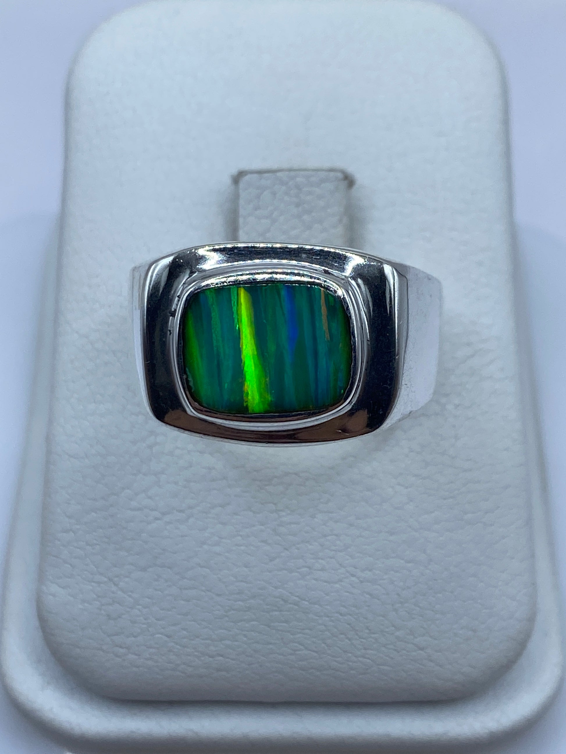 Anillo de plata .950 con opalo de fuego verde en la mano, mostrando el juego de colores