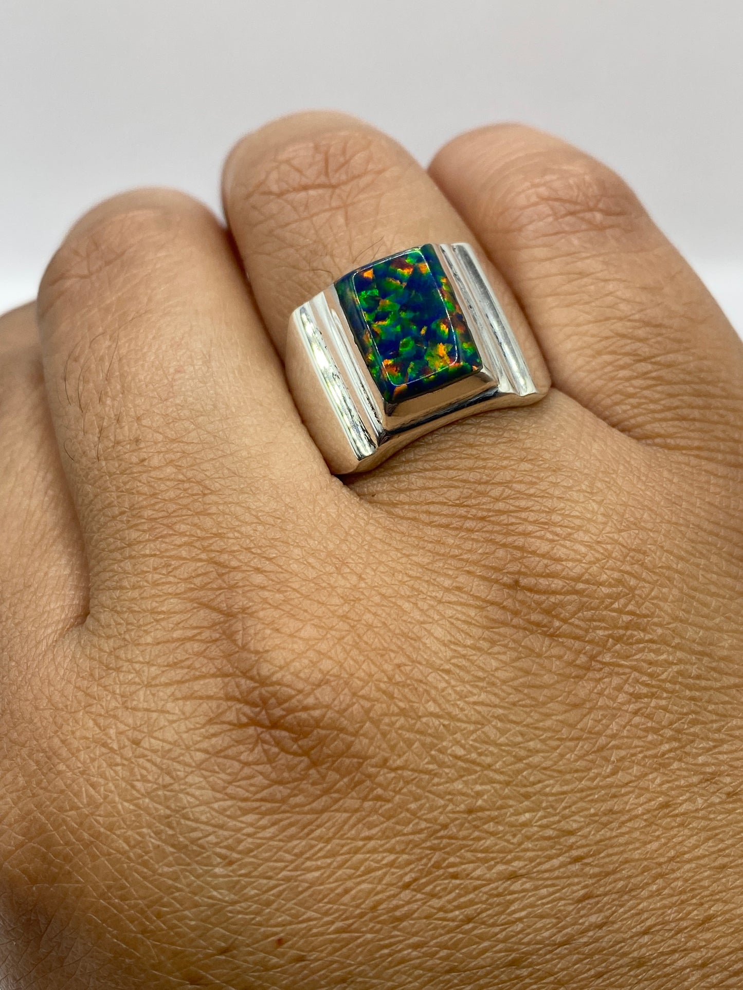 Anillo ópalo de fuego en dedo de hombre mostrando presencia y brillo natural