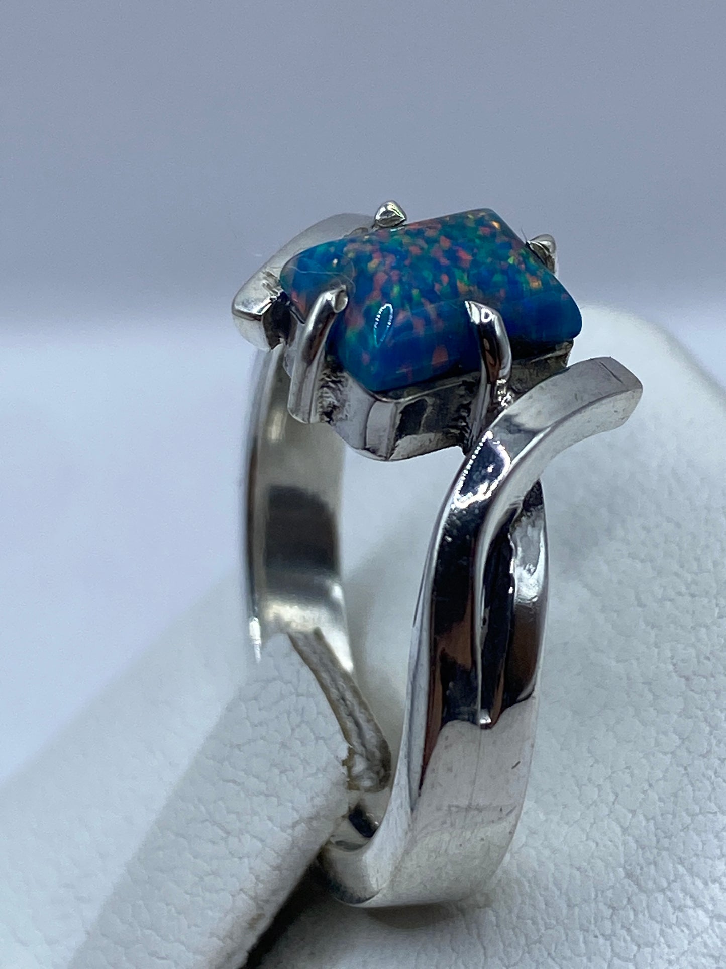 Anillo ópalo de fuego en la mano mostrando el juego de color azul