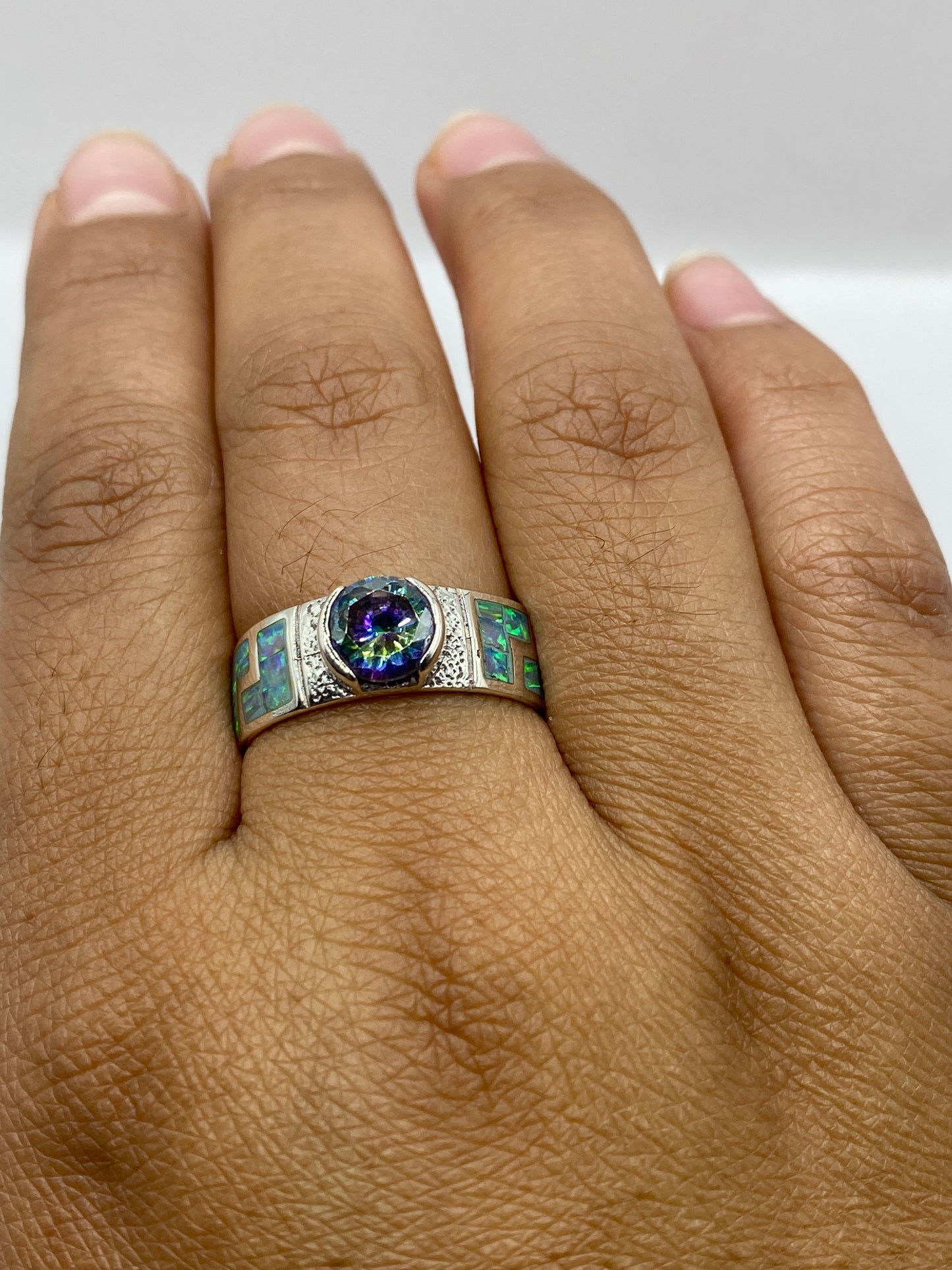 Anillo en mano mostrando el brillo vivo del ópalo y la textura artesanal de la plata de Taxco