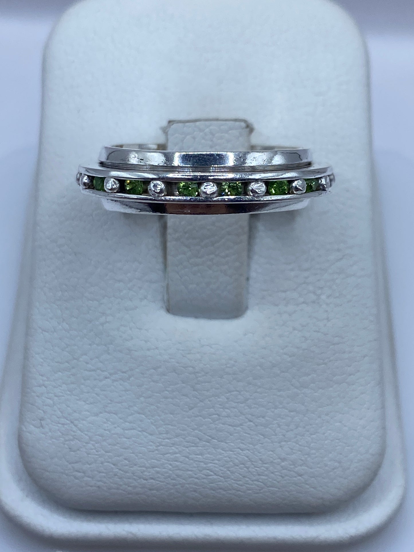 Anillo de plata eslabones con circonias verdes brillantes en mano de mujer