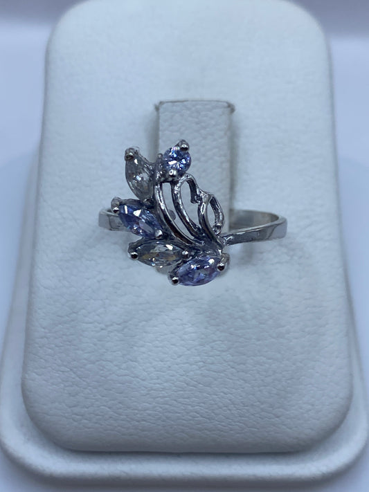 Anillo de plata minimalista con circonias multicolor brillante en la mano de una mujer