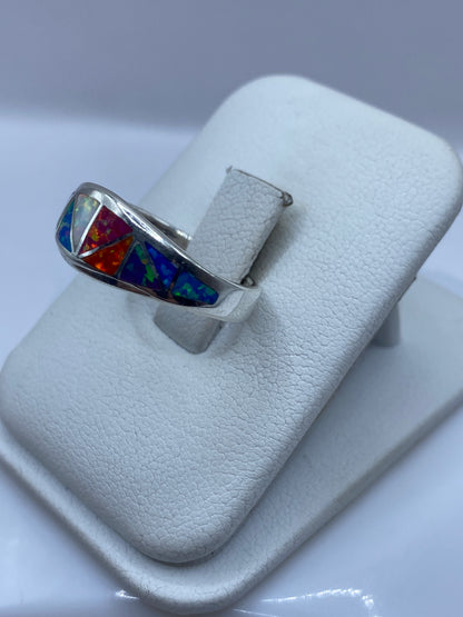 Vista lateral del anillo con ópalo exhibiendo naranja, rojo y azul bajo la luz