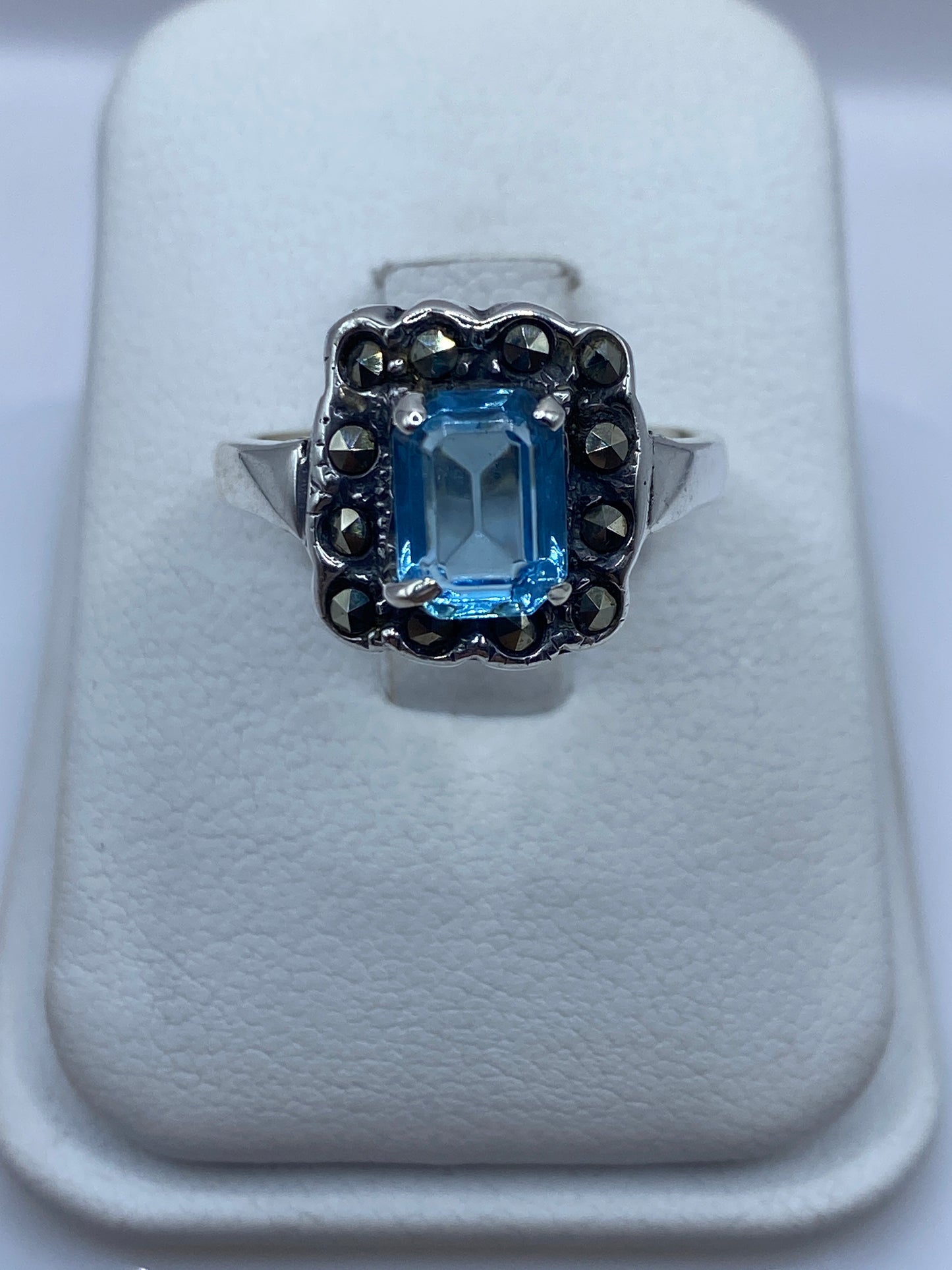 Anillo de plata solitario con circonia azul cielo en la mano de una mujer