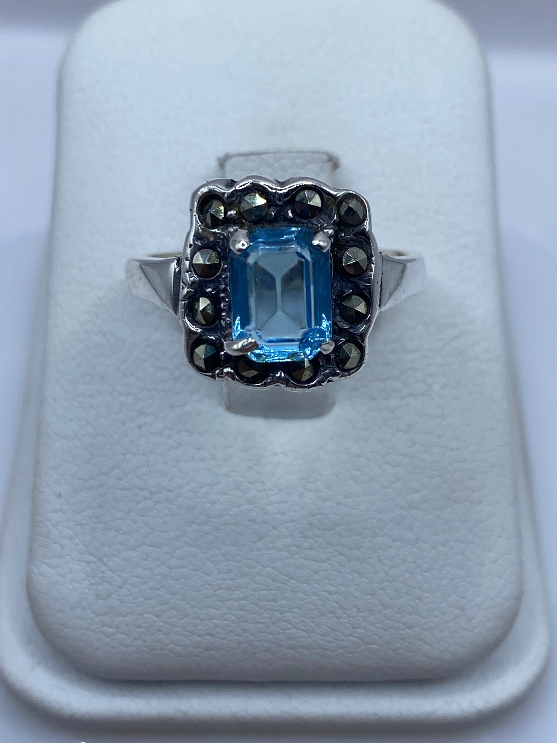 Anillo de plata solitario con circonia azul cielo en la mano de una mujer