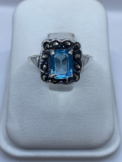 Anillo de plata solitario con circonia azul cielo en la mano de una mujer