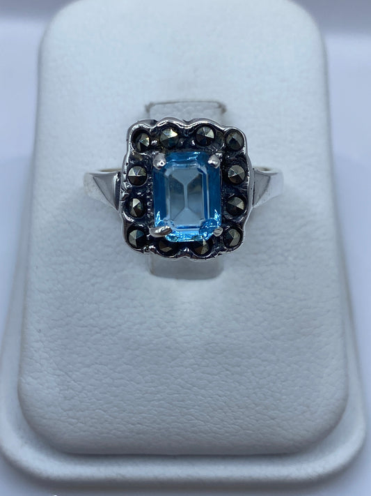 Anillo de plata solitario con circonia azul cielo en la mano de una mujer