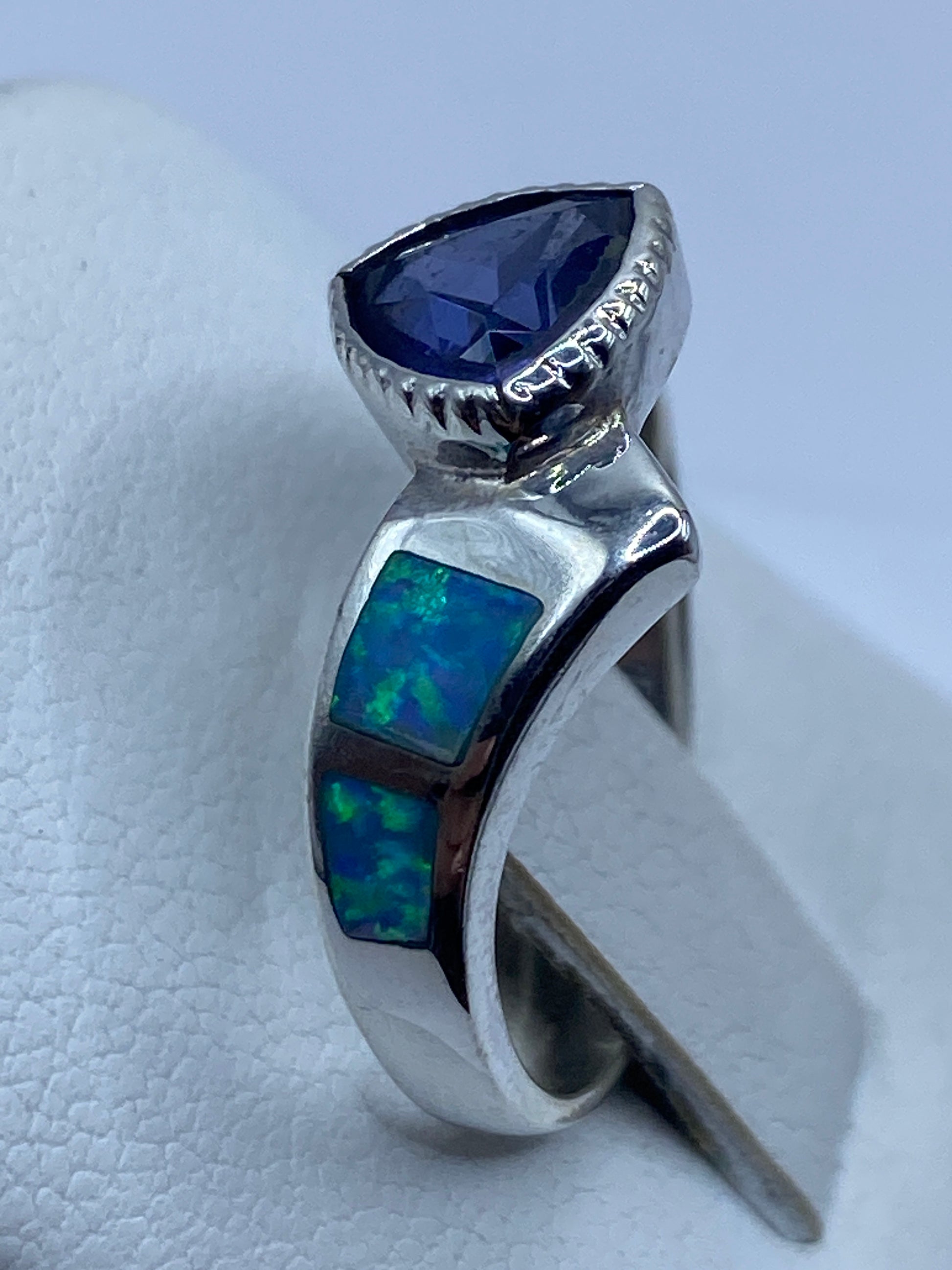 Anillo con ópalo de fuego en la mano, capturando los reflejos azules y verdes de la piedra
