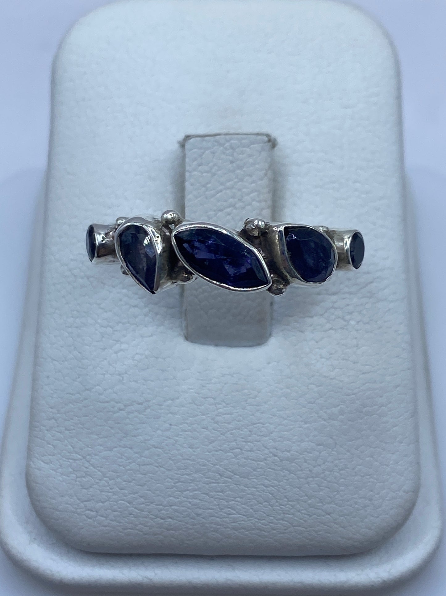 Anillo de plata minimalista con tres circonias azules en asimetría sobre banda pulida