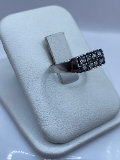 Anillo solitario en plata sobre dedo mostrando el engaste de circonia blanca