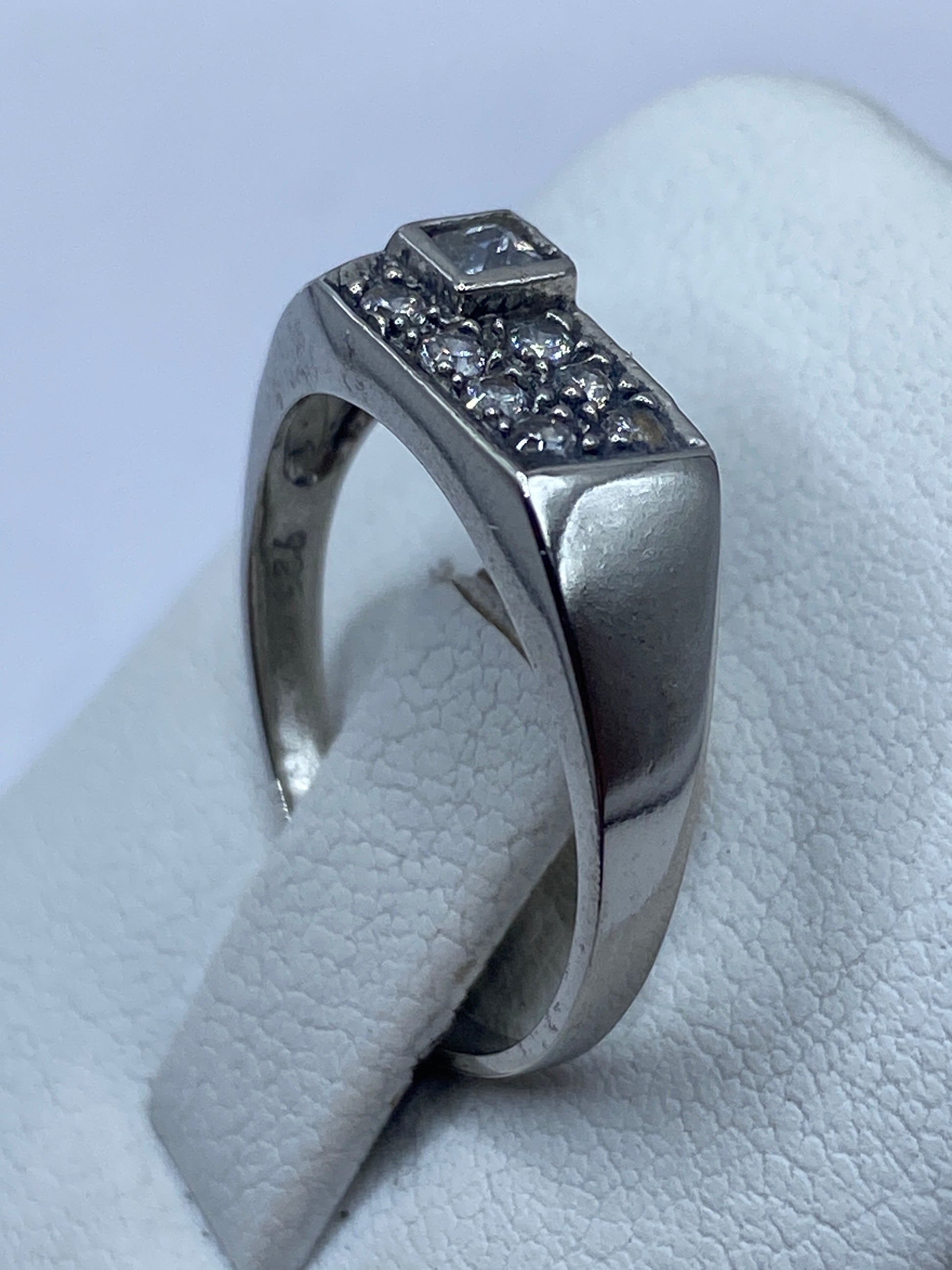 Detalle lateral del anillo de plata pulida con piedra circular brillante