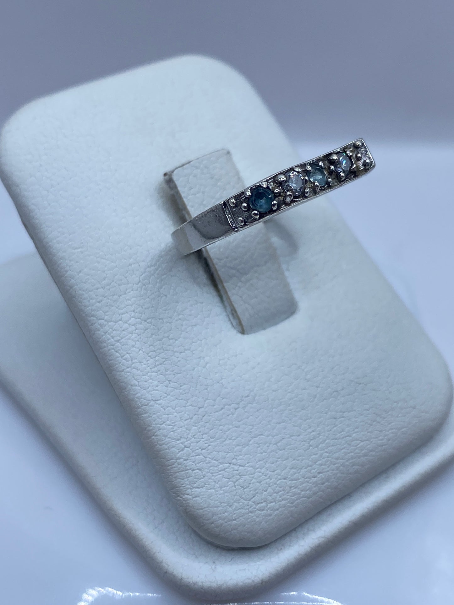 Anillo solitario de plata .925 sobre dedo, mostrando la circonia azul en luz natural