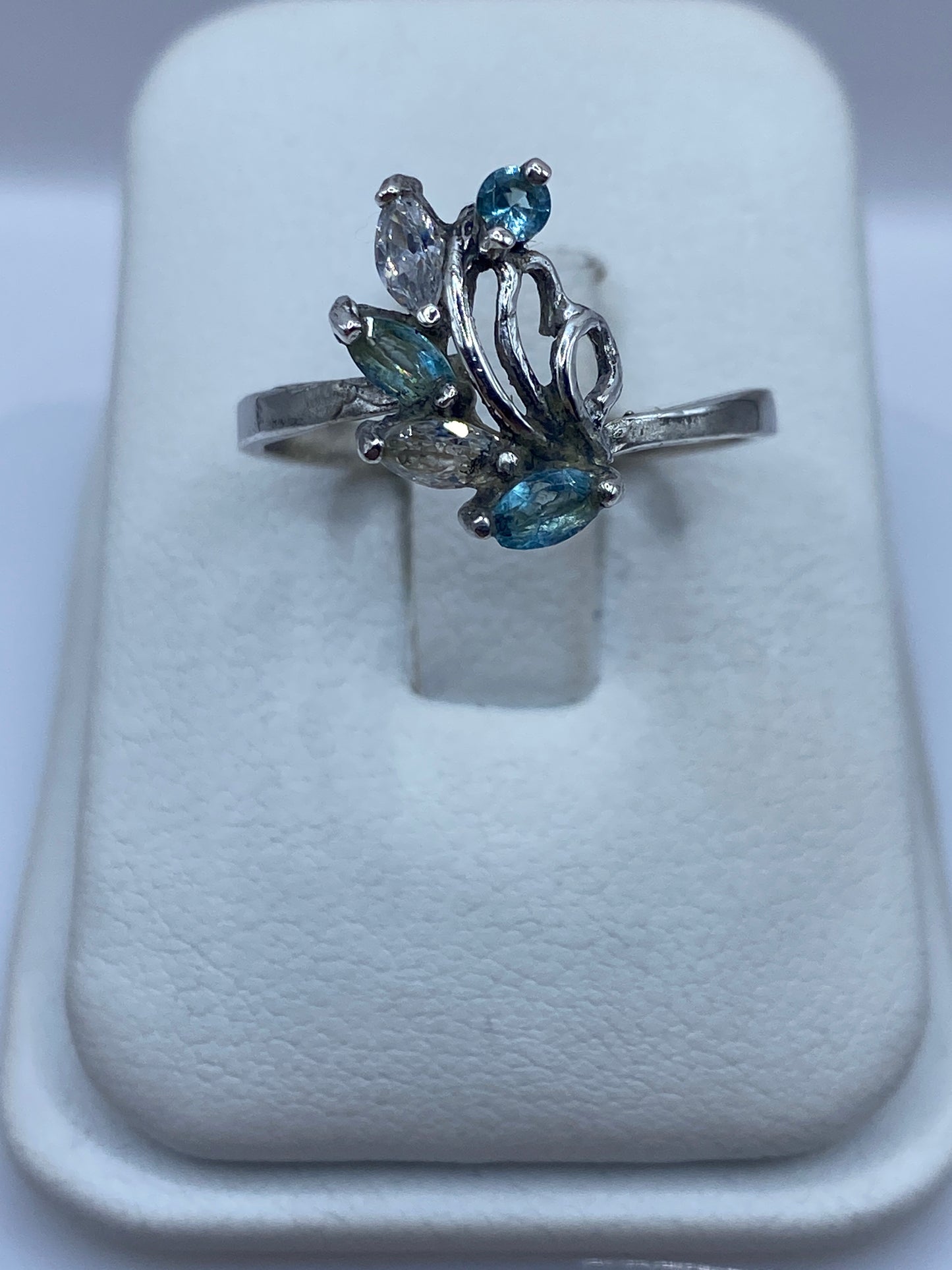 Anillo de plata solitario con circonia azul cielo en la mano de una mujer