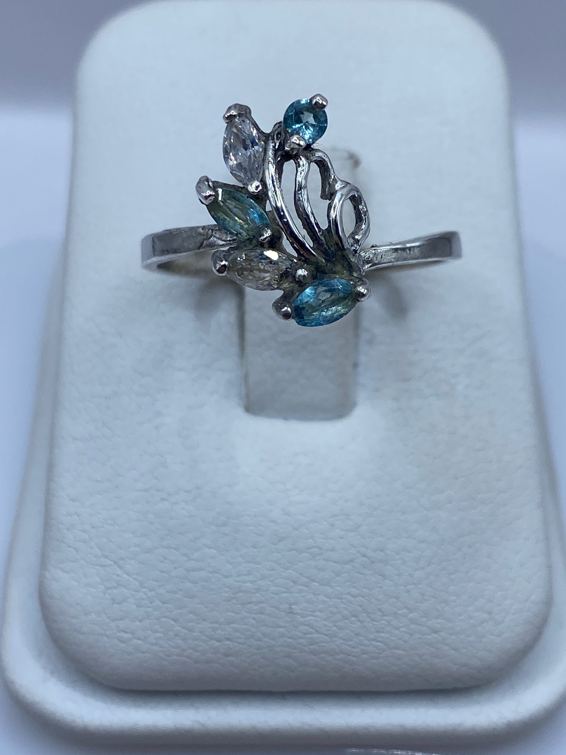 Anillo de plata solitario con circonia azul cielo en la mano de una mujer