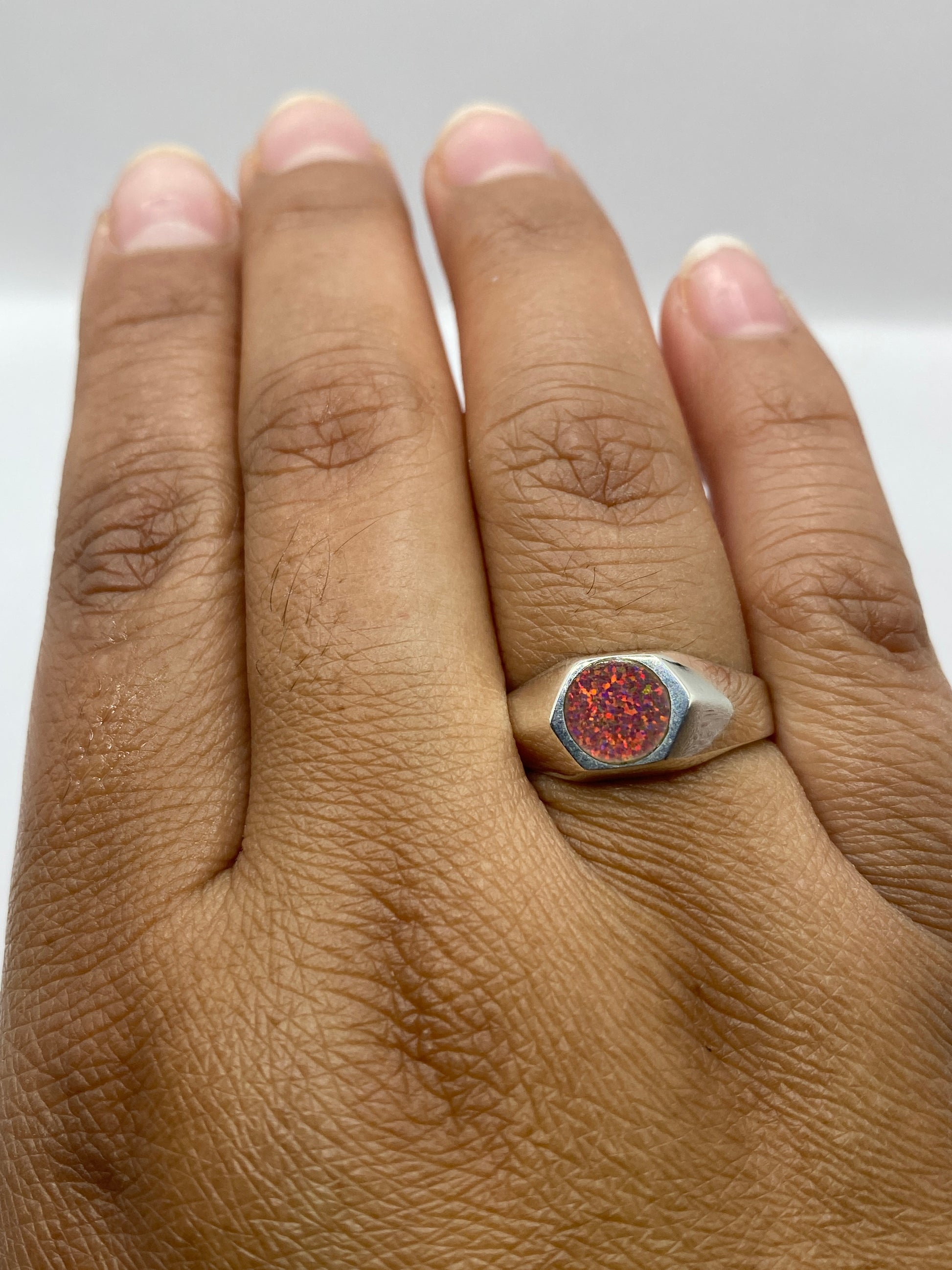 Anillo en dedo mostrando el fuego rosa del ópalo bajo luz natural