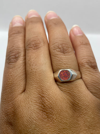 Anillo en dedo mostrando el fuego rosa del ópalo bajo luz natural