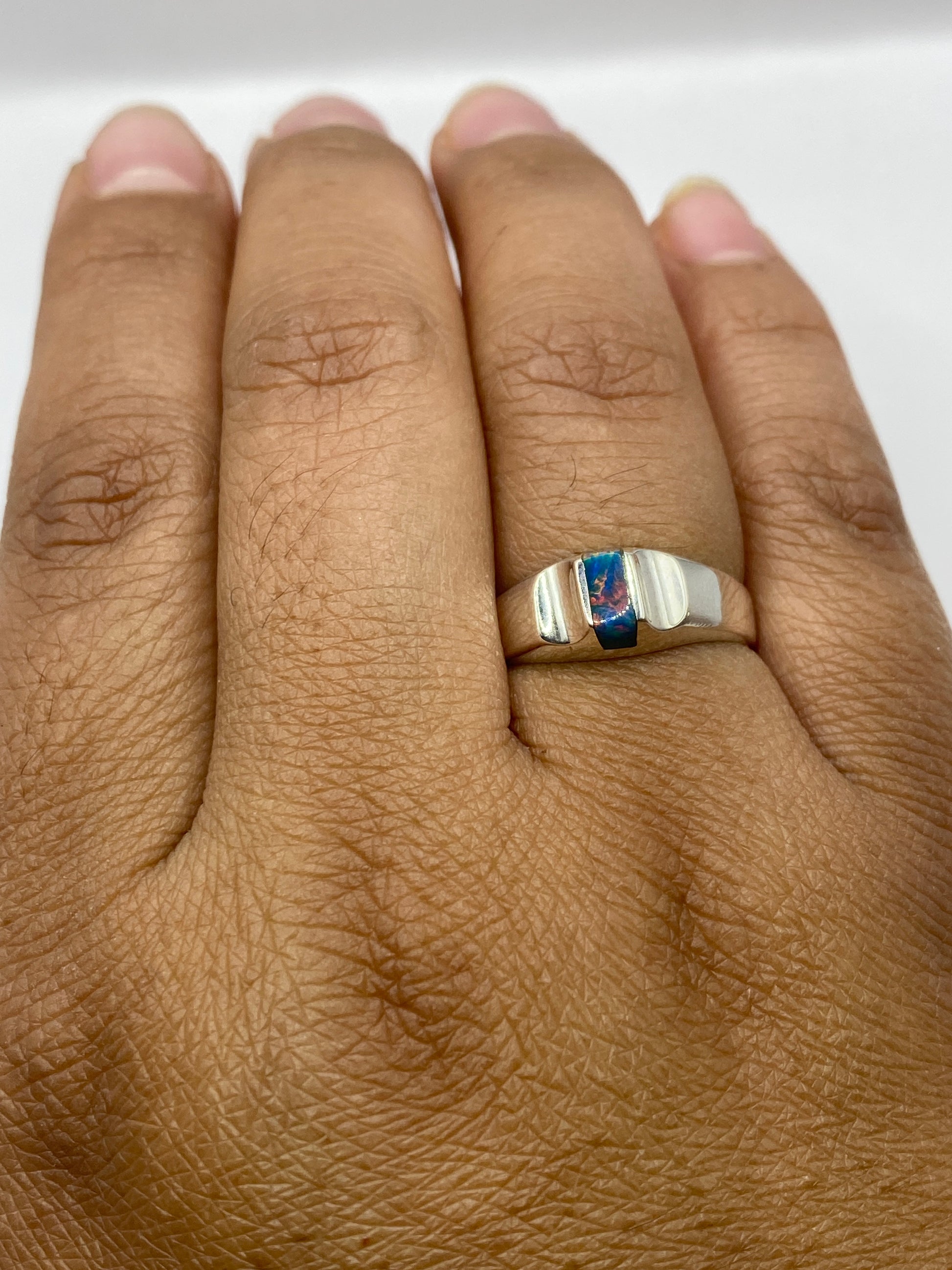 Anillo ópalo fuego azul en la mano mostrando el brillo y fuego natural de la piedra