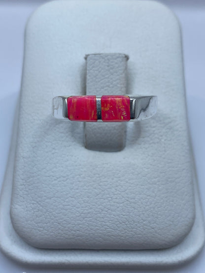 Anillo de plata minimalista con ópalo de fuego rosa en la mano de una mujer