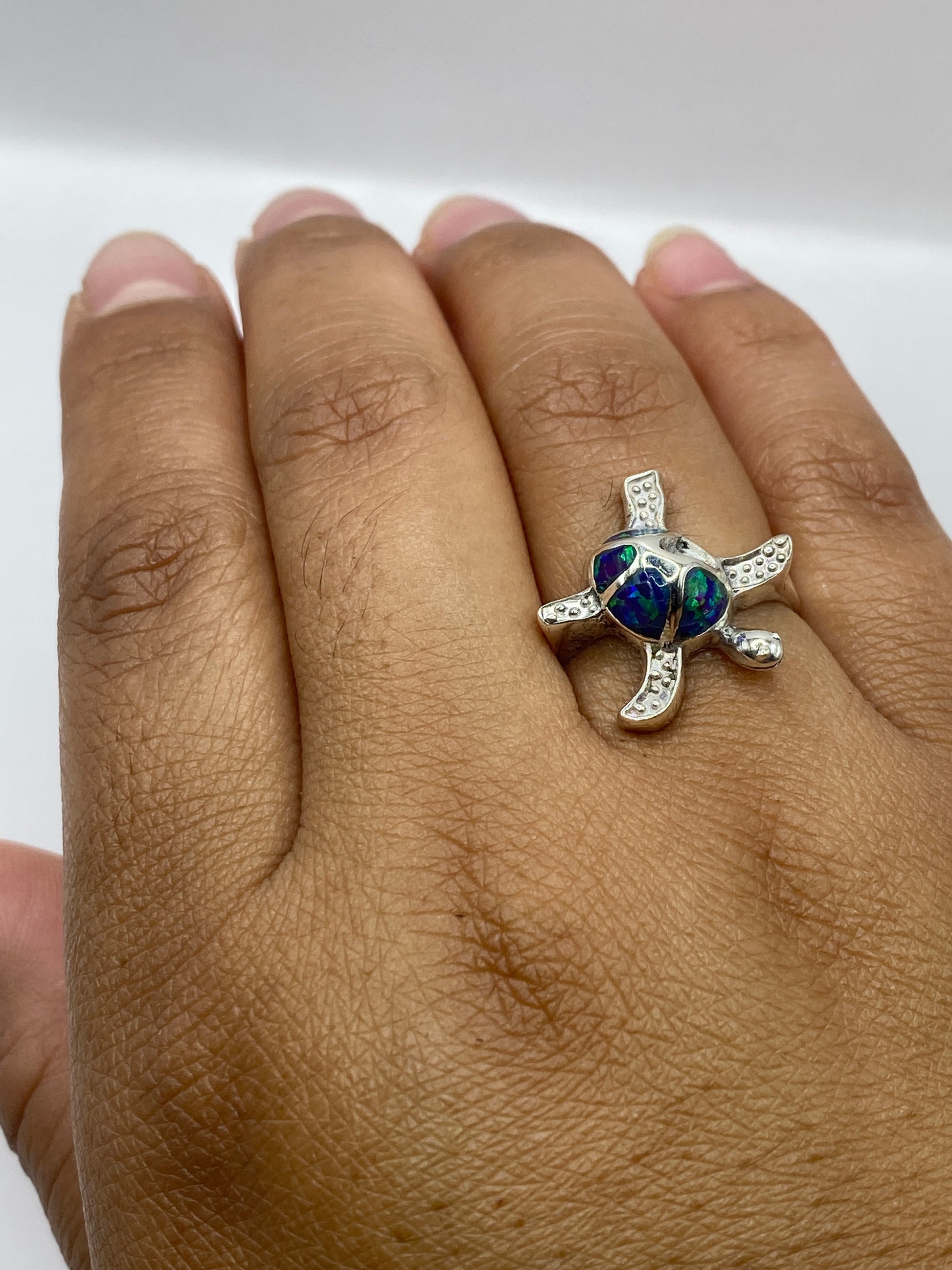 Anillo en mano de mujer mostrando el brillo y los tonos naranja-rojo del ópalo