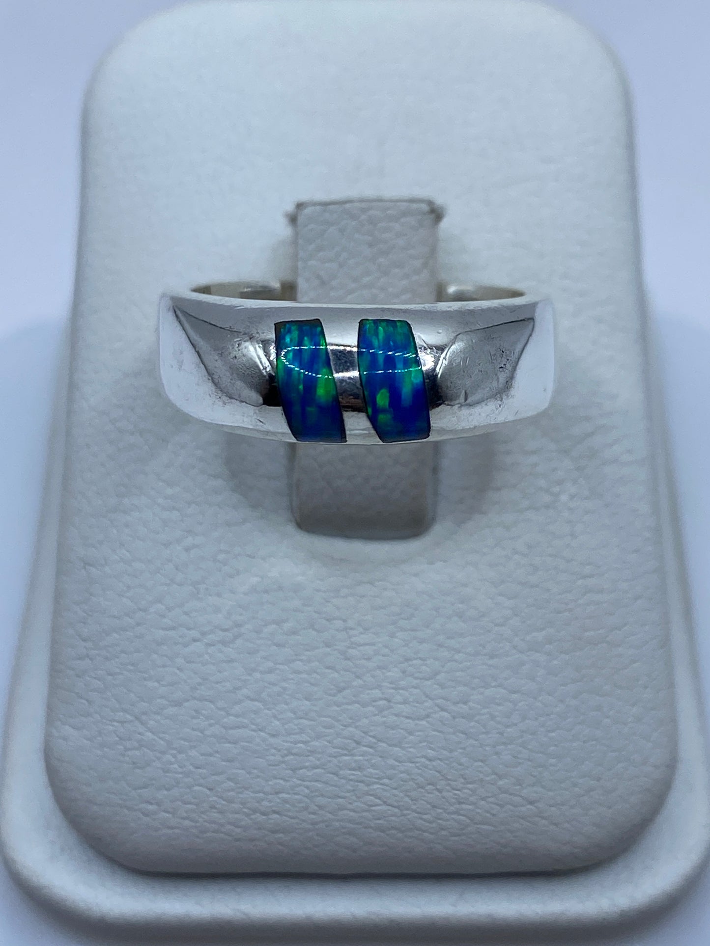 Anillo de plata con ópalo de fuego azul sobre caja blanca, frente directo
