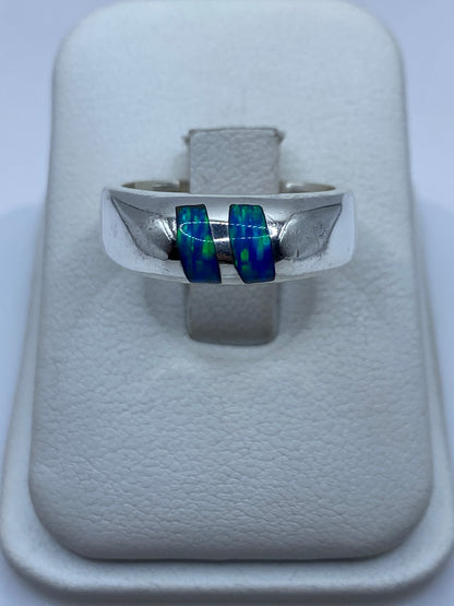 Anillo de plata con ópalo de fuego azul sobre caja blanca, frente directo