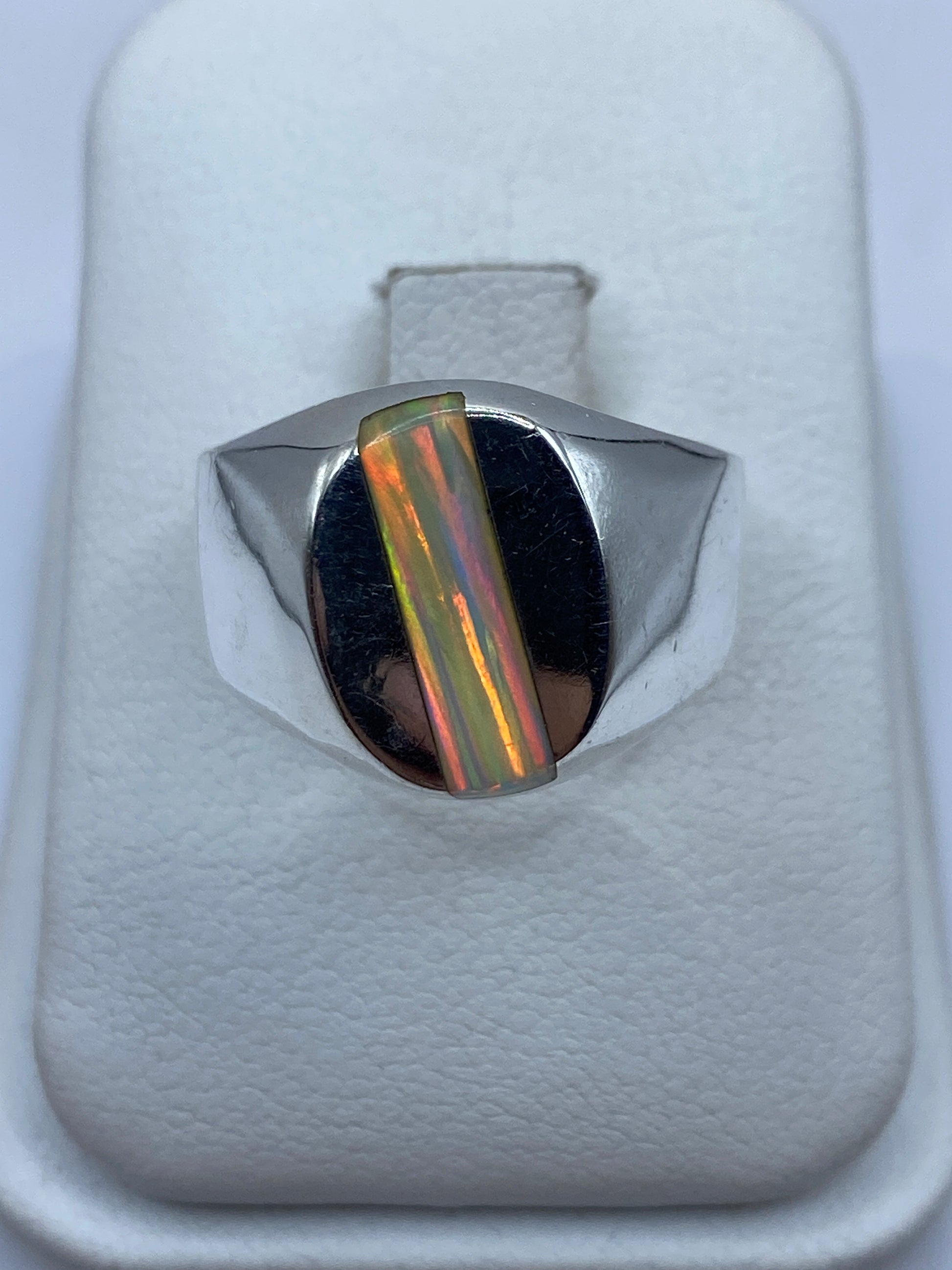 Anillo de plata macizo con ópalo de fuego multicolor en la mano de un hombre