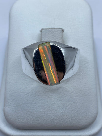 Anillo de plata macizo con ópalo de fuego multicolor en la mano de un hombre