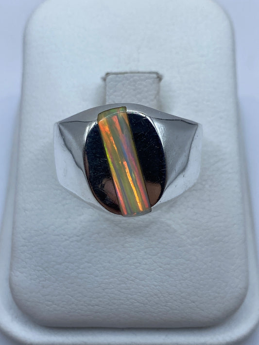 Anillo de plata macizo con ópalo de fuego multicolor en la mano de un hombre