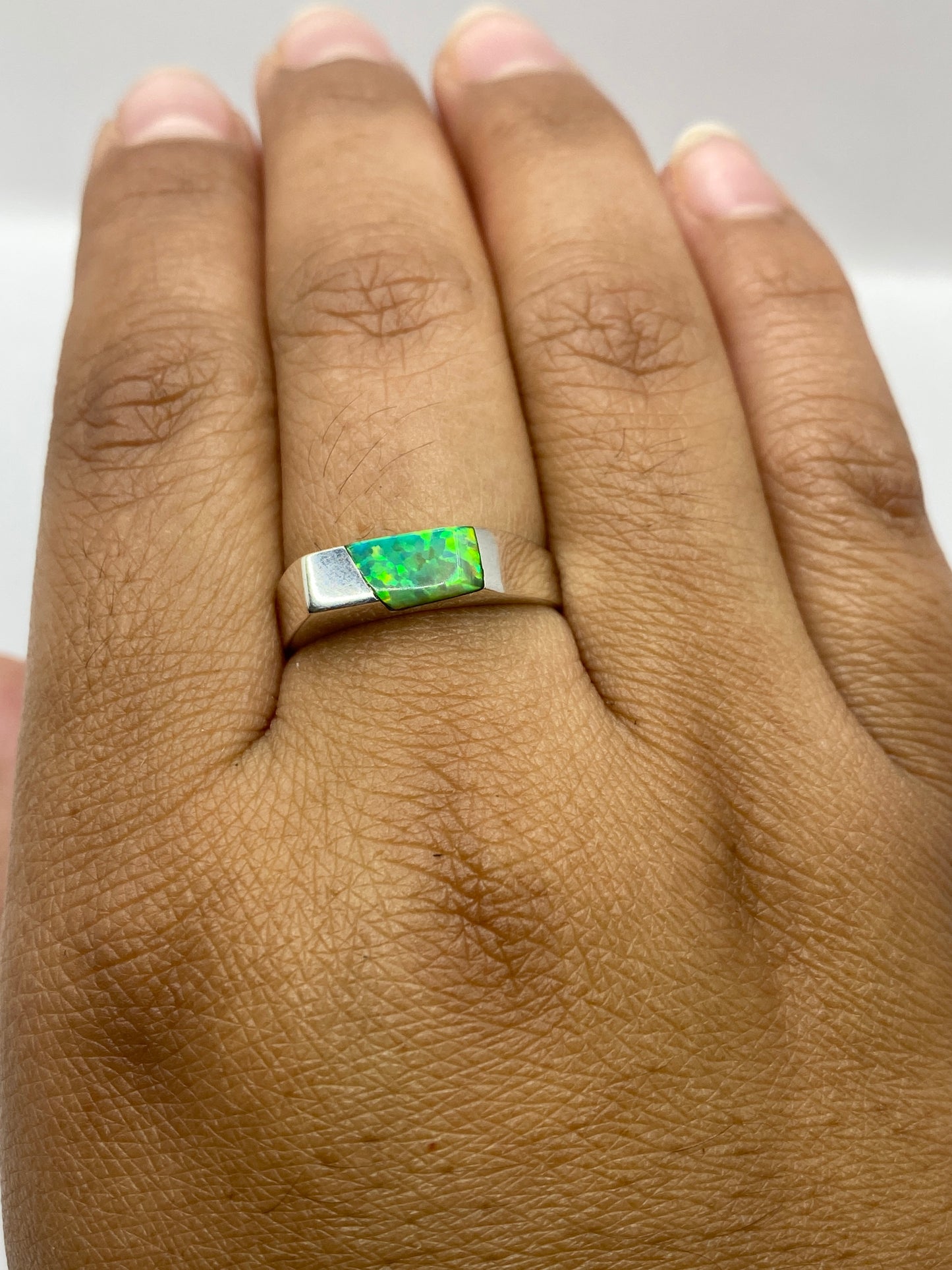 Anillo geométrico de plata pura en dedo mostrando la piedra ópalo de fuego único