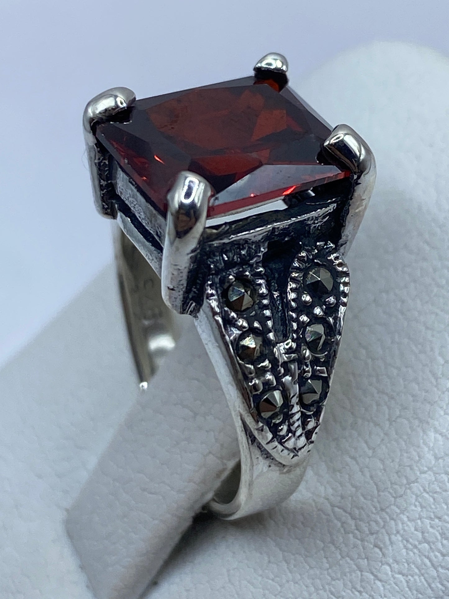Anillo solitario circonia roja en la mano, brillando con fuego intenso