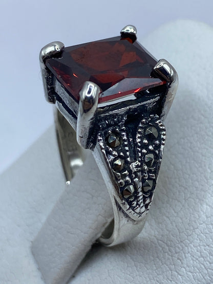 Anillo solitario circonia roja en la mano, brillando con fuego intenso
