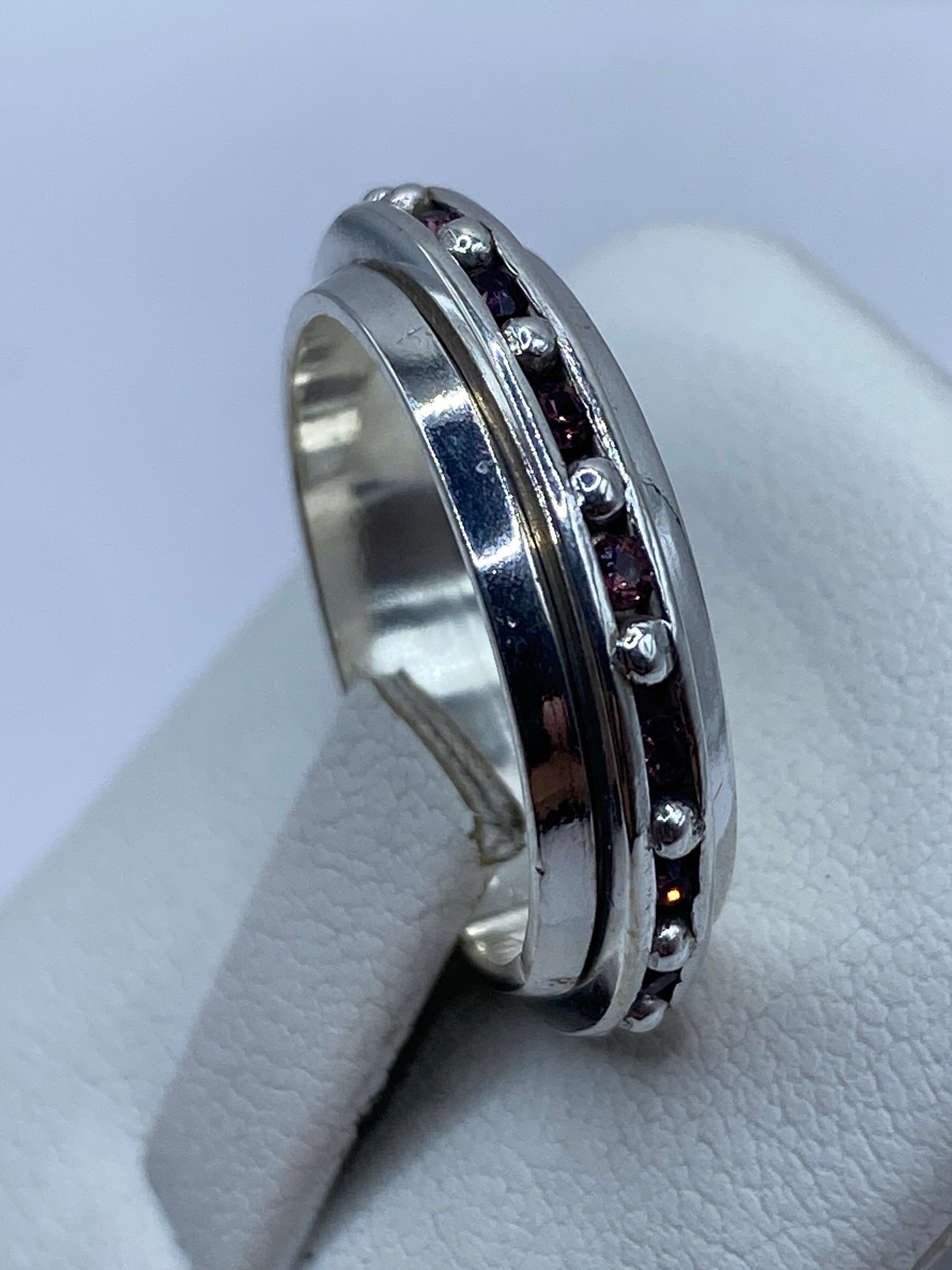 Anillo giratorio en la mano de una mujer, con circonia rosa captando la luz