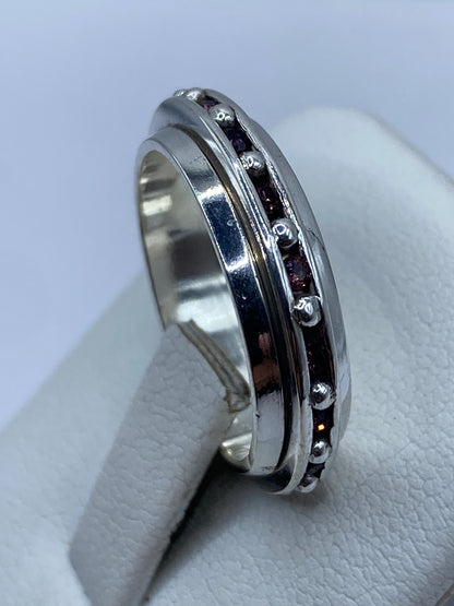 Anillo giratorio en la mano de una mujer, con circonia rosa captando la luz