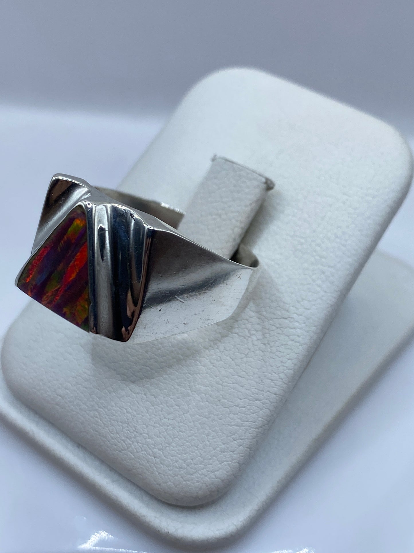 Vista frontal del anillo geométrico con ópalo de fuego natural mostrando reflejos rojo, naranja y verde