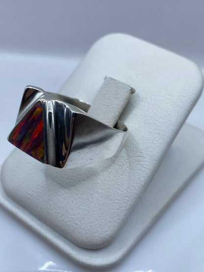Vista frontal del anillo geométrico con ópalo de fuego natural mostrando reflejos rojo, naranja y verde