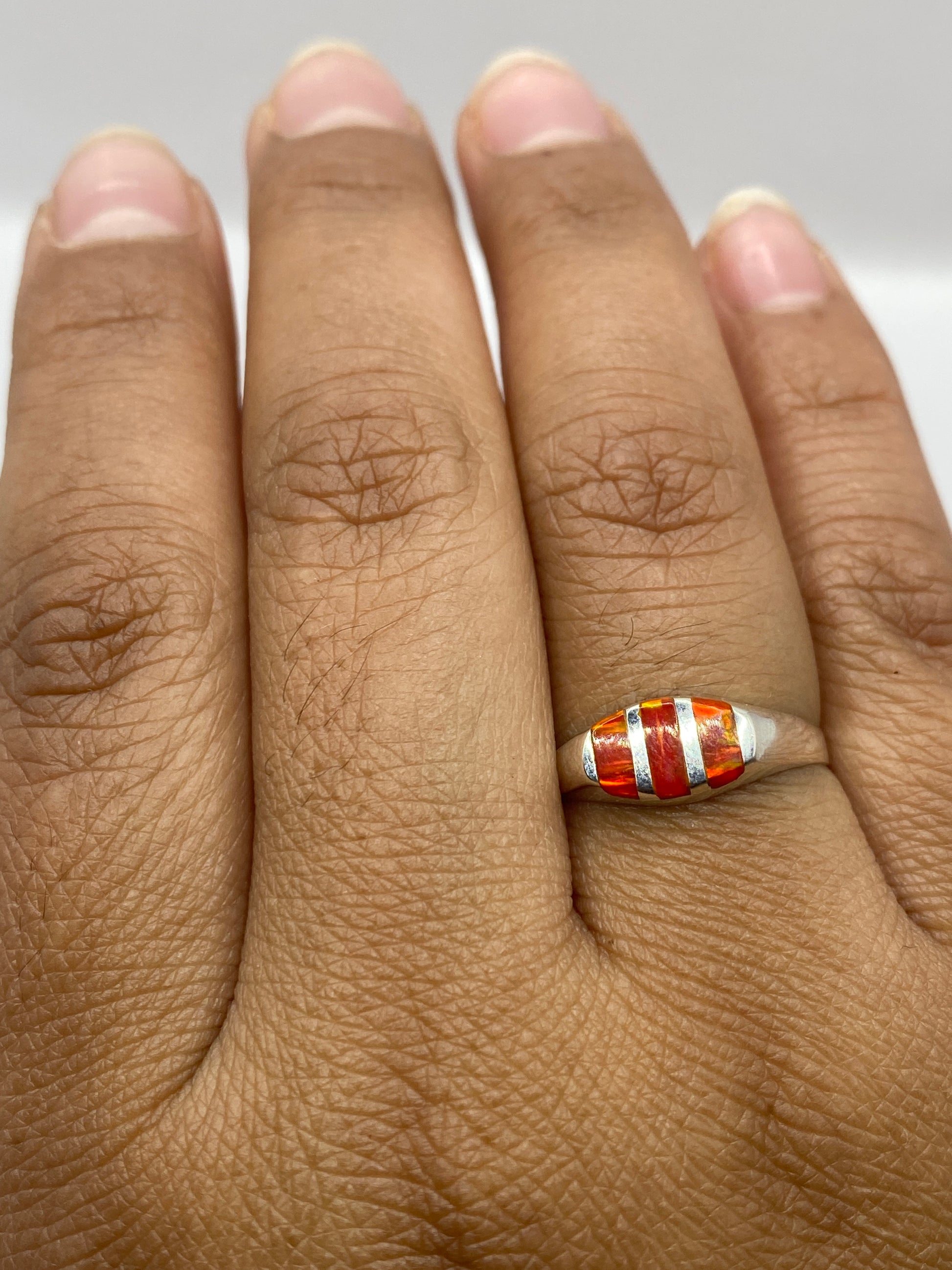 Anillo sobre fondo gris mostrando la profundidad del color naranja del ópalo