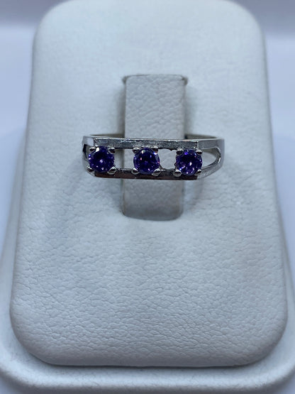 Anillo de plata solitario con circonia morada facetada sobre almohada blanca