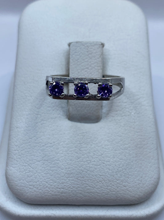Anillo de plata solitario con circonia morada facetada sobre almohada blanca