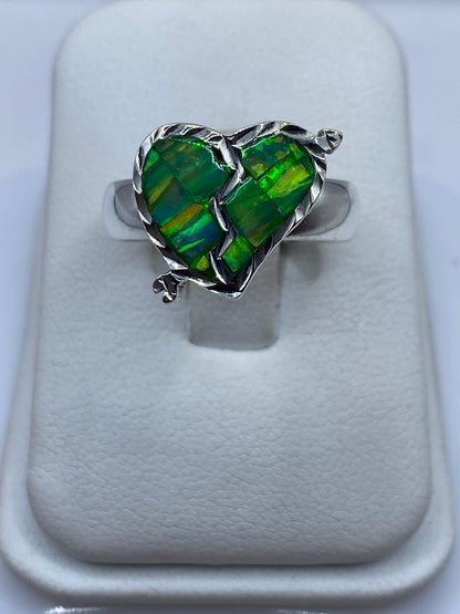 Anillo de plata corazón con circonia verde limón en la mano de una mujer