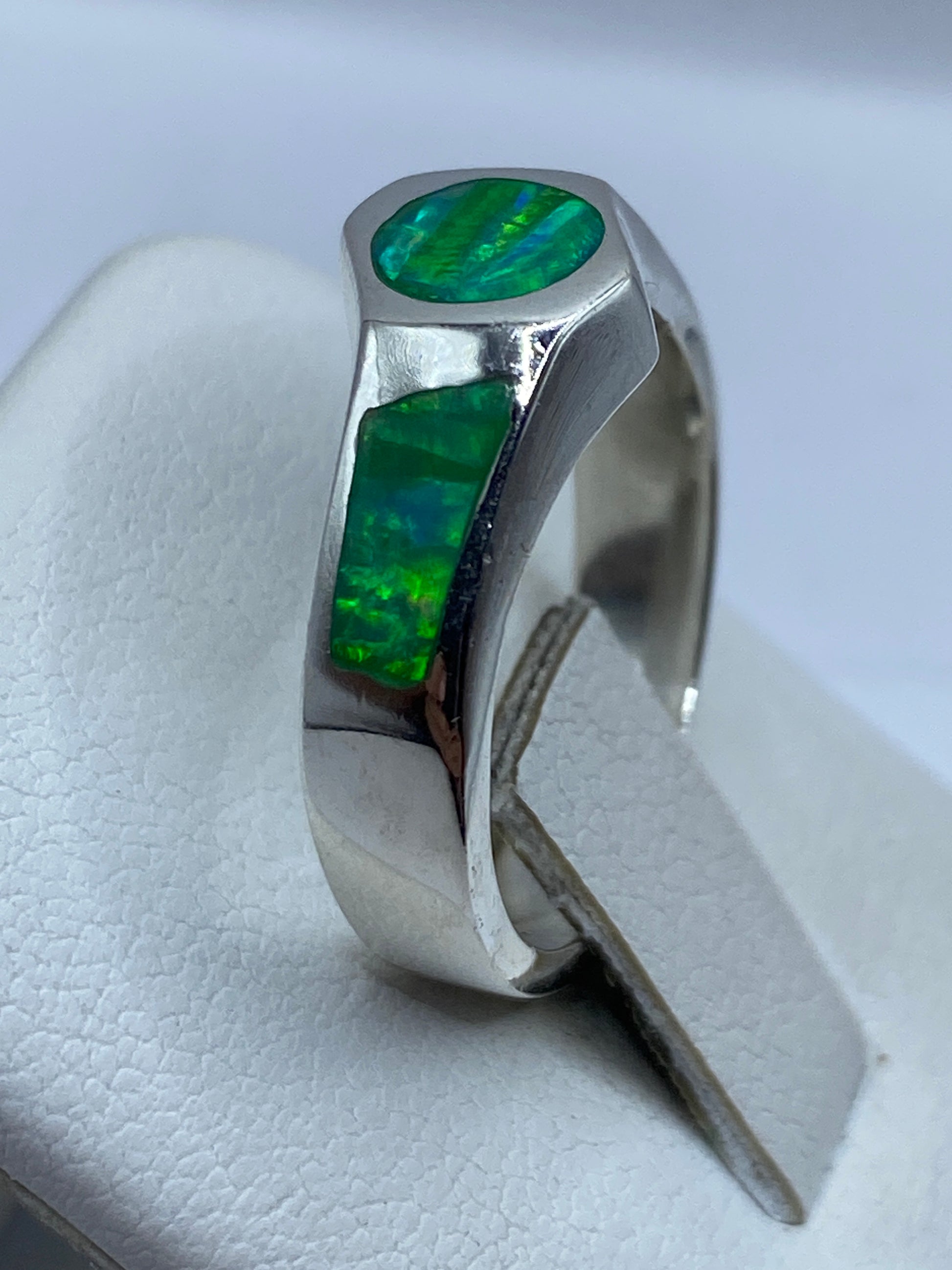 Ópalo de fuego verde con reflejos azules y amarillos en la mano, anillo de plata pura